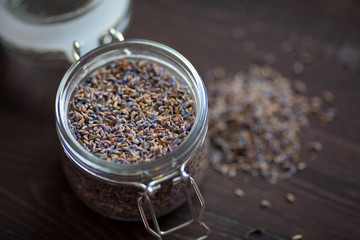Dry lavender flowers in a glass pot on a dark wooden background