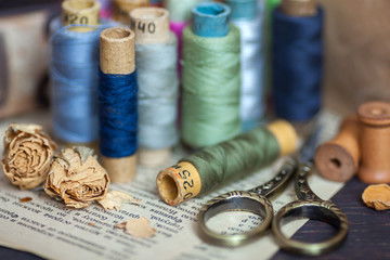 Vintage composition with old threads, scissors, wooden bobbins and dry flowers