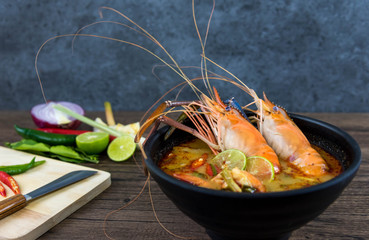 Close up Asian Spicy soup with shrimp in bowl , famous Thai food cuisineม Tom Yum Goong Spicy Sour Soup on wooden table top view