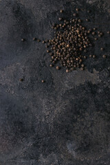 Heap of black pepper peppercorns over old black iron texture background. Top view, copy space.