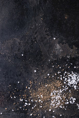 Groung black pepper powder and sea salt over old black iron texture surface. Top view, space. Food...