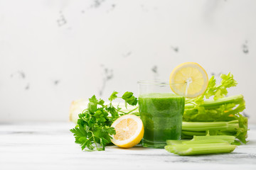 Green cocktail smoothie parsley celery lemon lime slices, healthy drink ingredients, glass of beverage on white wooden table, detox diet clean eating, with vegetables on table