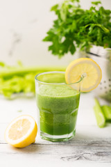 Green cocktail smoothie parsley celery lemon lime slices, healthy drink ingredients, glass of beverage on white wooden table, detox diet clean eating, with vegetables on table