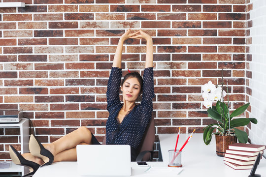 Relaxed business woman with legs on the desk in office extending