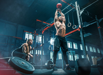 Fit young man lifting barbells working out in a gym