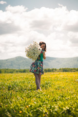 Fototapeta premium Beautiful young girl with a huge bouquet of daisies on a boundless field happy. Beautiful advertising background