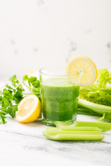 Green cocktail smoothie parsley celery lemon lime slices, healthy drink ingredients, glass of beverage on white wooden table, detox diet clean eating, with vegetables on table