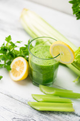 Green cocktail smoothie parsley celery lemon lime slices, healthy drink ingredients, glass of beverage on white wooden table, detox diet clean eating, with vegetables on table