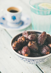 Traditional muslim food for Ramadan iftar meal. Dates, glass of water and coffee over wooden table.