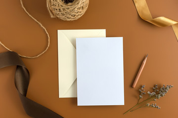 A wedding concept. Wedding Invitation, envelopes, cards Papers on brown background with ribbon and decoration. Top view, flat lay, copy space