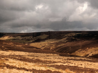 a view of oxenhope moor in west yorkshire with brown dry grass and heather against a grey dramatic cloudy sky