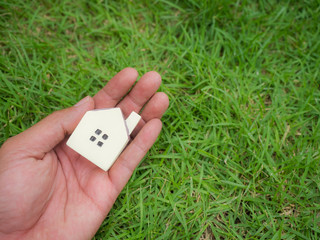 Small House model on hand in green grass field.