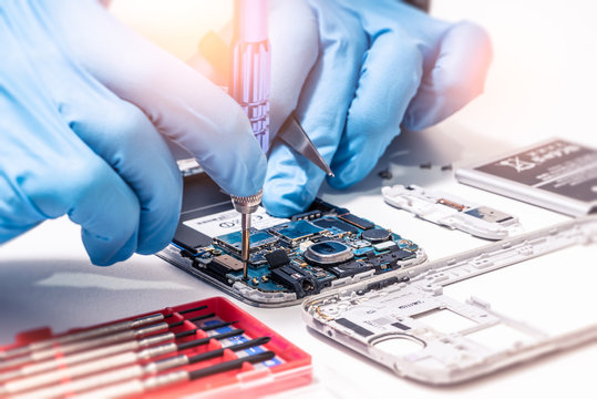 The abstract image of the technician assembling inside of smartphone by screwdriver in the lab. the concept of computer hardware, mobile phone, electronic, repairing, upgrade and technology.