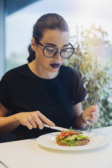 Young attractive girl is eating bruschetta at business lunch