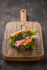 Tasty breakfast sandwich with lettuce, ham, cheese and tomato.