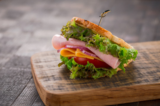 Tasty breakfast sandwich with lettuce, ham, cheese and tomato.