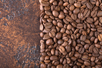 Black roasted coffee grains lie on a copper table.