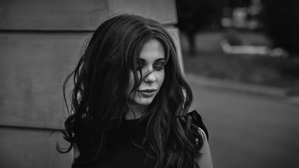 Gothic young brunette woman outdoors with wind in hair, shallow depth of field