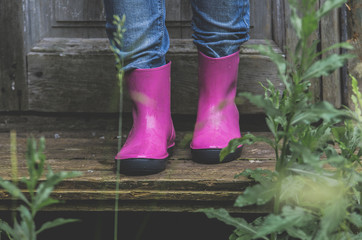 A woman in bright rubber boots of magenta color