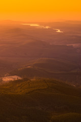 Orange gold sunrise light creeping over hills, valleys and rivers at Gods Window in Mpumalanga South Africa