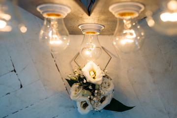 The wedding bouquet stands near lamps