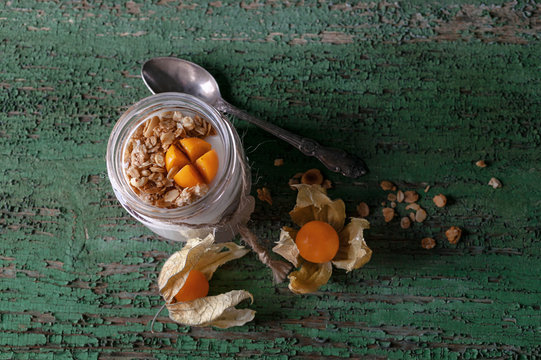 Homemade yogurt in a jar with berries of fesalis on rustic background.