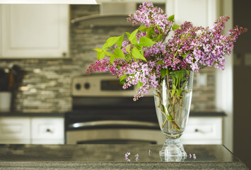 Bouquet of lilac on kitchen table, kitchen interior blurred background