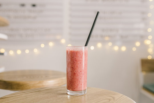 Healthy Organic Pink Fruit And Vegetable And Herb Smoothie Served On A Rustic Wooden Table At A Bar Against A Brown Bokeh Of Twinkling Lights With Copyspace.