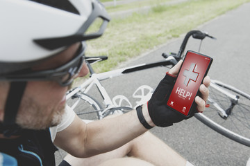 Injured biker holding his smartphone calling rescue team