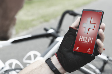 Injured biker holding his smartphone calling rescue team
