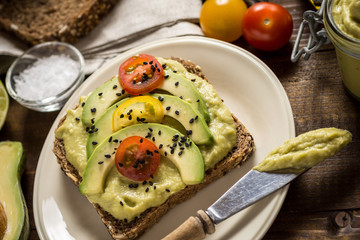 Avocado Spread Guacamole and Slices with Fresh Cherry Tomato and Black Sesame. Healthy Breakfast Concept.