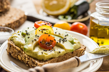 Fototapeta na wymiar Avocado Spread Guacamole and Slices with Fresh Cherry Tomato and Black Sesame. Healthy Breakfast Concept.
