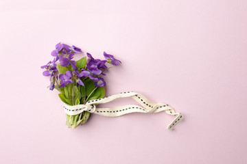 violet flowers in bouquet on pink background, flat lay. Spring, summer romantic minimal concept