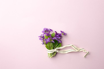 violet flowers in bouquet on pink background, flat lay. Spring, summer romantic minimal concept