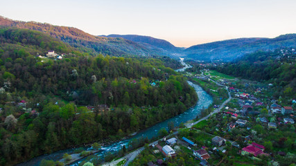 Fototapeta na wymiar Drone view of mountains and Plastunka village in the valley of the Sochi river in spring evening, Sochi, Russia 