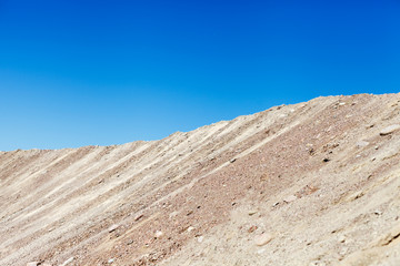 Каменно-песочный склон на фоне голубого неба