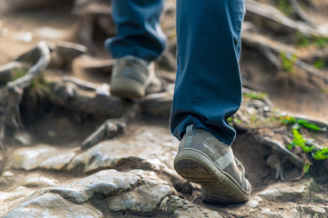 the tourist climbs up the hill on slippery stones, legs close-up