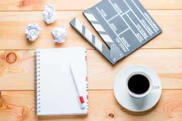 Naklejka premium a notebook, a cup of coffee and a clapper for shooting movie episodes on wooden boards