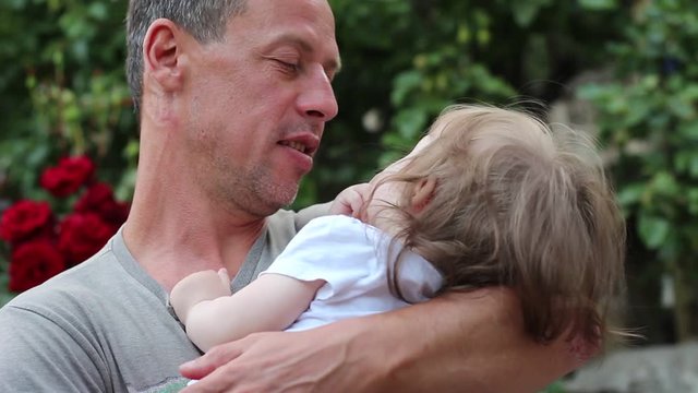 Father lulls child. 40+ year old man and baby. Adult male with gray hair