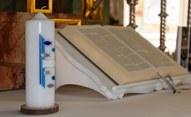 Taufkerzen mit Arrangement und Bibel. Weiße Taufkerzen für besondere Anlässe in der Kirche.