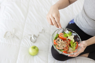 Enjoyed Asian woman eating vegetable salad.