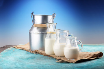 A jug of milk and glass of milk on a wooden table