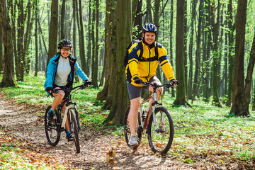 Obraz premium couple riding bicycle in forest in warm day