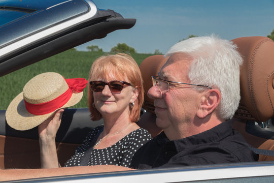 Happy Older Couple Drives With A Luxury Convertible Car On A Sunny Day