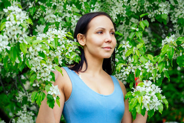 beautiful brunette woman in a sporty blue suit against a background of flowering spring trees