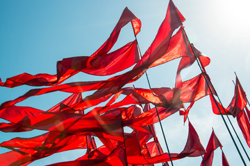 Scarlet flags in the wind against the blue sky shot against the sun. In backlight. Best summer.