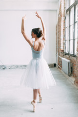 A young ballerina is getting ready, stretched and dancing. Poses in ballet. Photo shoot in the loft Studio. Russian Ballerina at the bench. ballet flats and dance dress