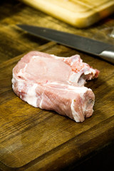 there is piece of raw meat for steak on a wooden table  background near knife on the kitchen
