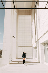 Beautiful stylish girl, street photo shoot with glasses and hat. Laughs, smiles and runs round. American processing in the photo. The lookbook of the collection street style