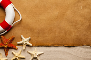 Fototapeta na wymiar Summer background - blank paper sheet, lifebuoy and starfish on sand